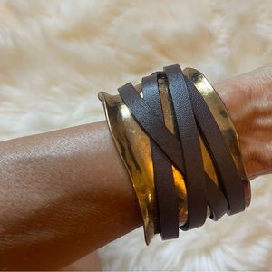 Uniquely shaped distressed gold cuff bracket w/brown leather wrap strap.